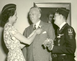 Sec. of Def. George C. Marshall receives buddy poppy from Mrs. Genevieve Frye, Pres. of the Auxiliary of American Legion Post 109, May 24, 1951