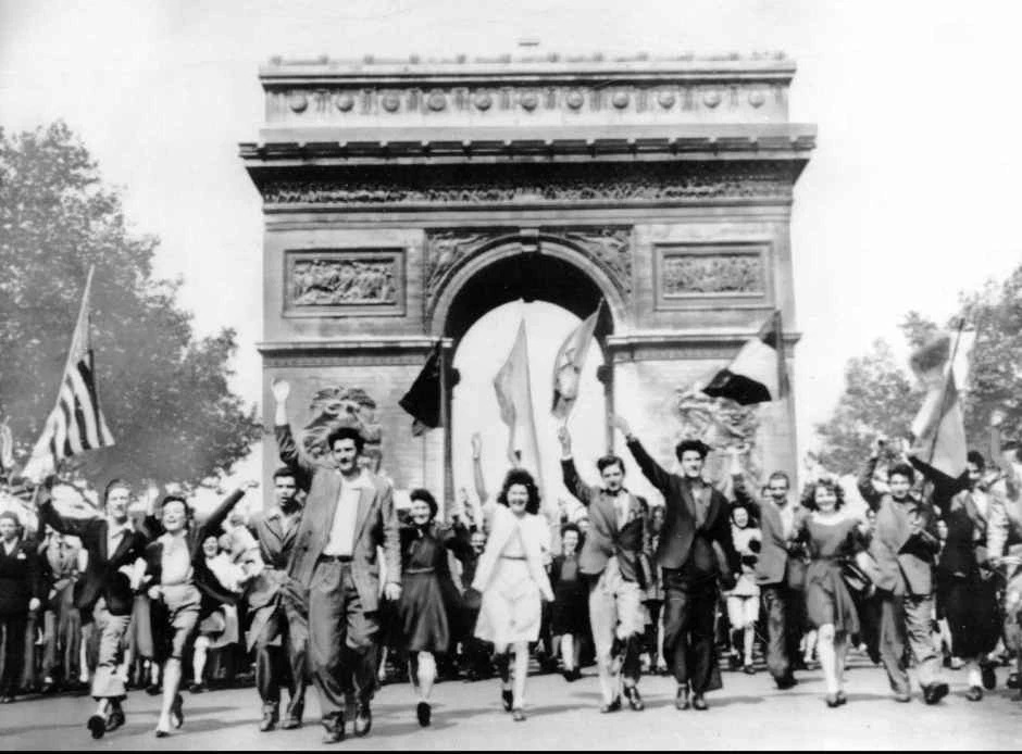 Crowds parade through the Arc de Triomphe in Paris during VE Day celebrations.