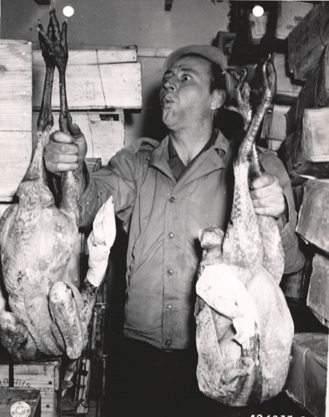 Pvt. William Brizee holds up two of thousands of turkeys stored for the U.S. Army.