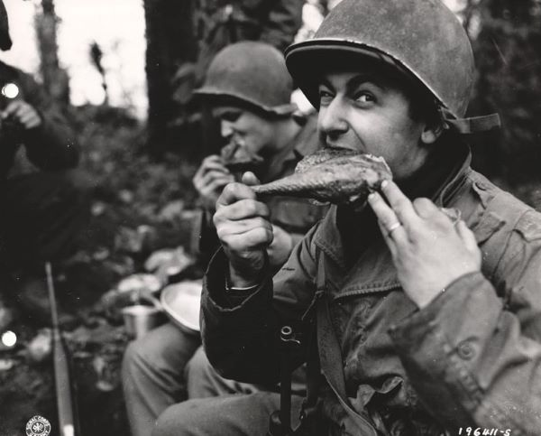 Soldiers devour the many turkeys that have been sent to them from  the United States. Corp. Leo Kaller struggles happily with a gobbler's leg.