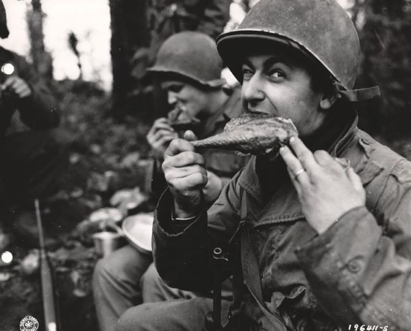 Soldiers devour the many turkeys that have been sent to them from the United States. Corp. Leo Kaller struggles happily with a gobbler's leg.